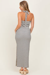 woman wearing a black and white striped halter neck maxi dress with side slits and a bow tie at the back