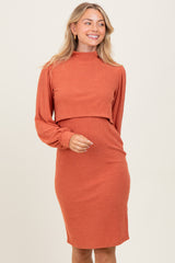 woman wearing a rust ribbed midi dress with long sleeves and a high neckline