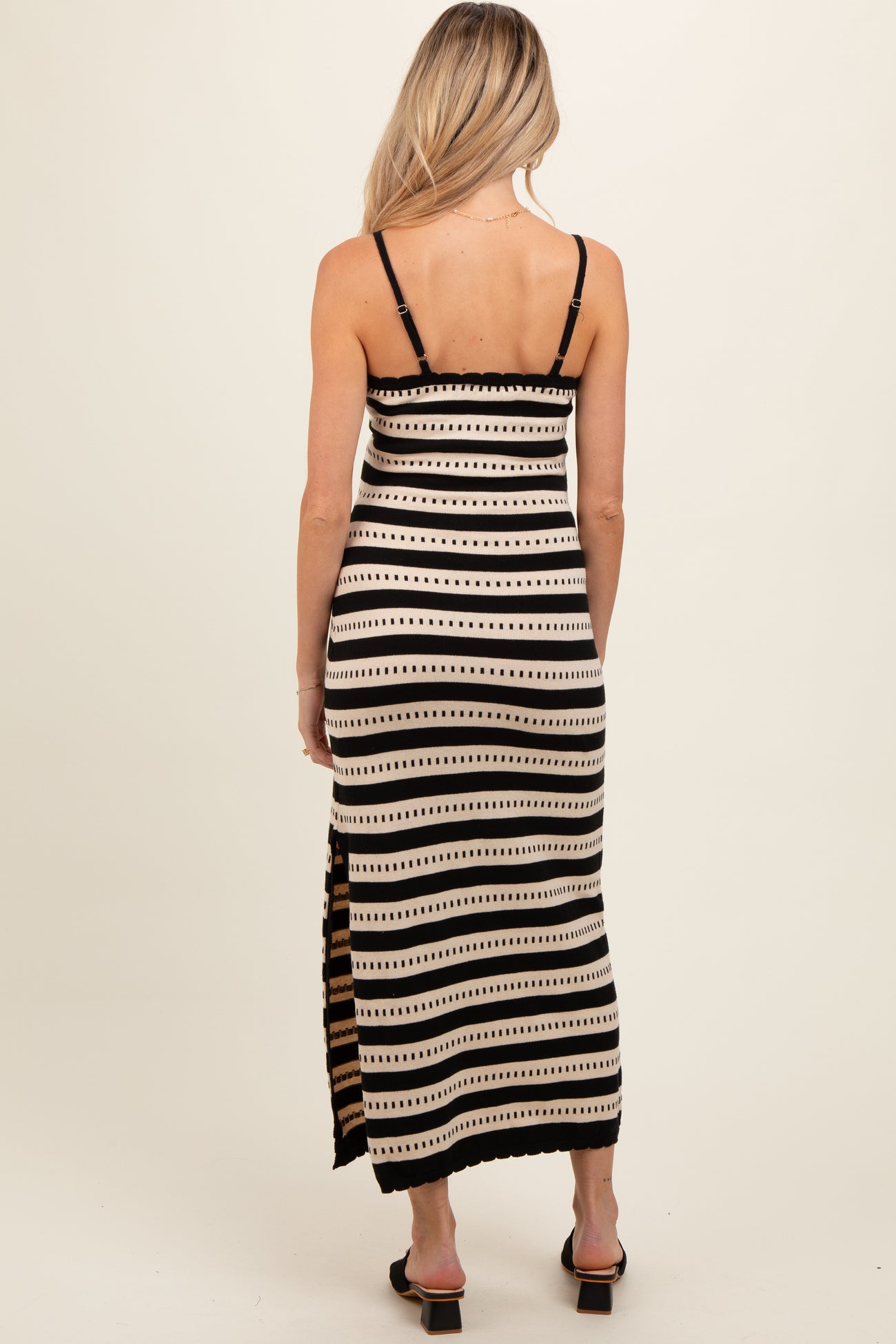woman wearing a black and white striped maternity maxi dress with adjustable straps and side slits