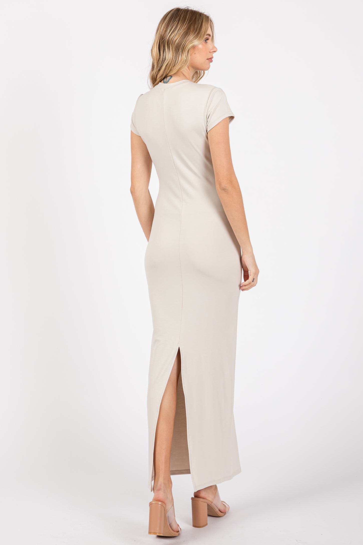 woman wearing a taupe short sleeve maxi dress with a back slit and a fitted silhouette