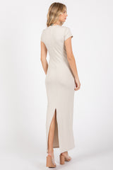 woman wearing a taupe short sleeve maxi dress with a back slit and a fitted silhouette