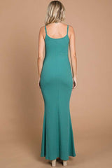 woman wearing a teal ribbed maxi dress with a fitted bodice and flared hem seen from the back