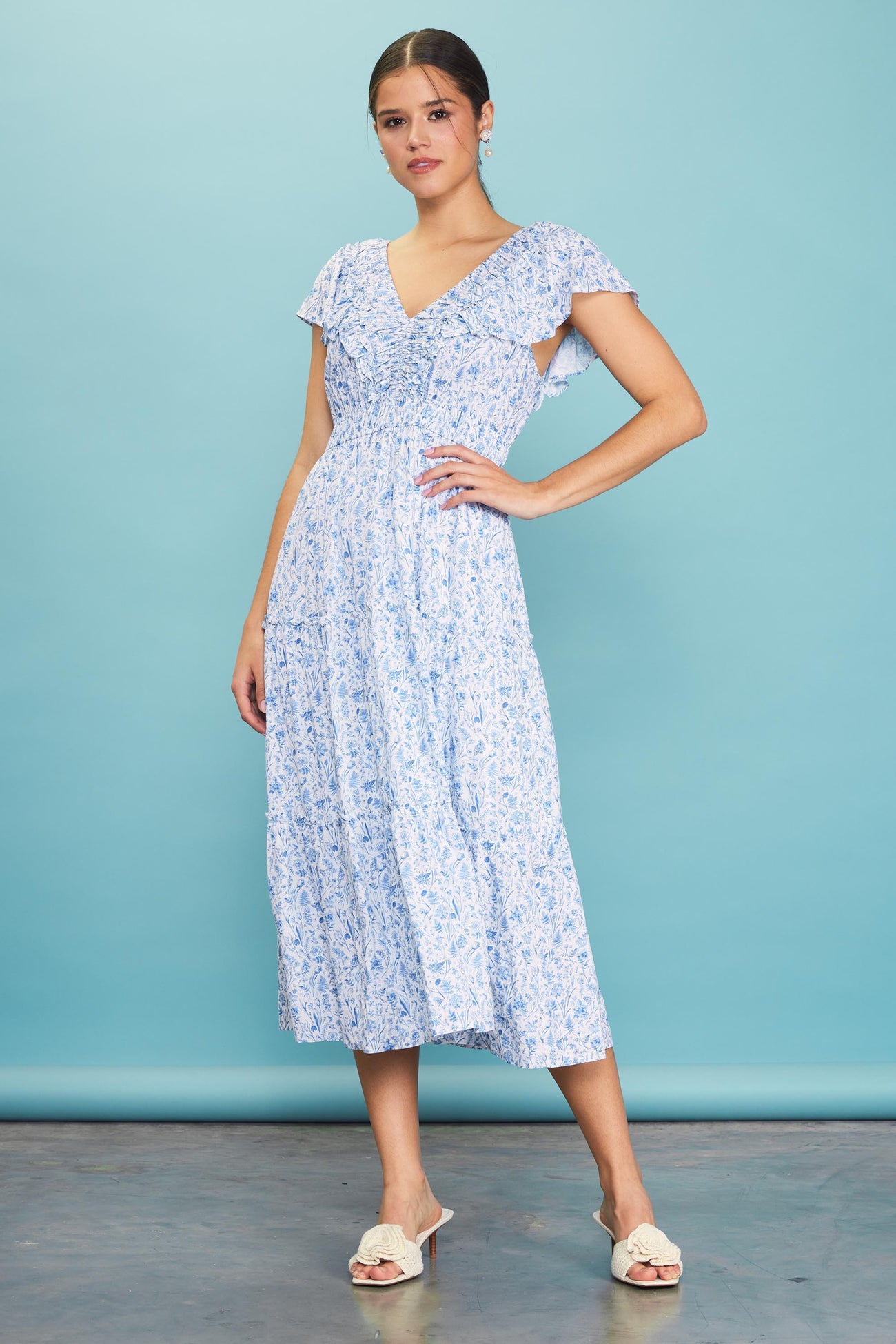 woman wearing a blue floral midi dress with ruffled sleeves and a v-neckline