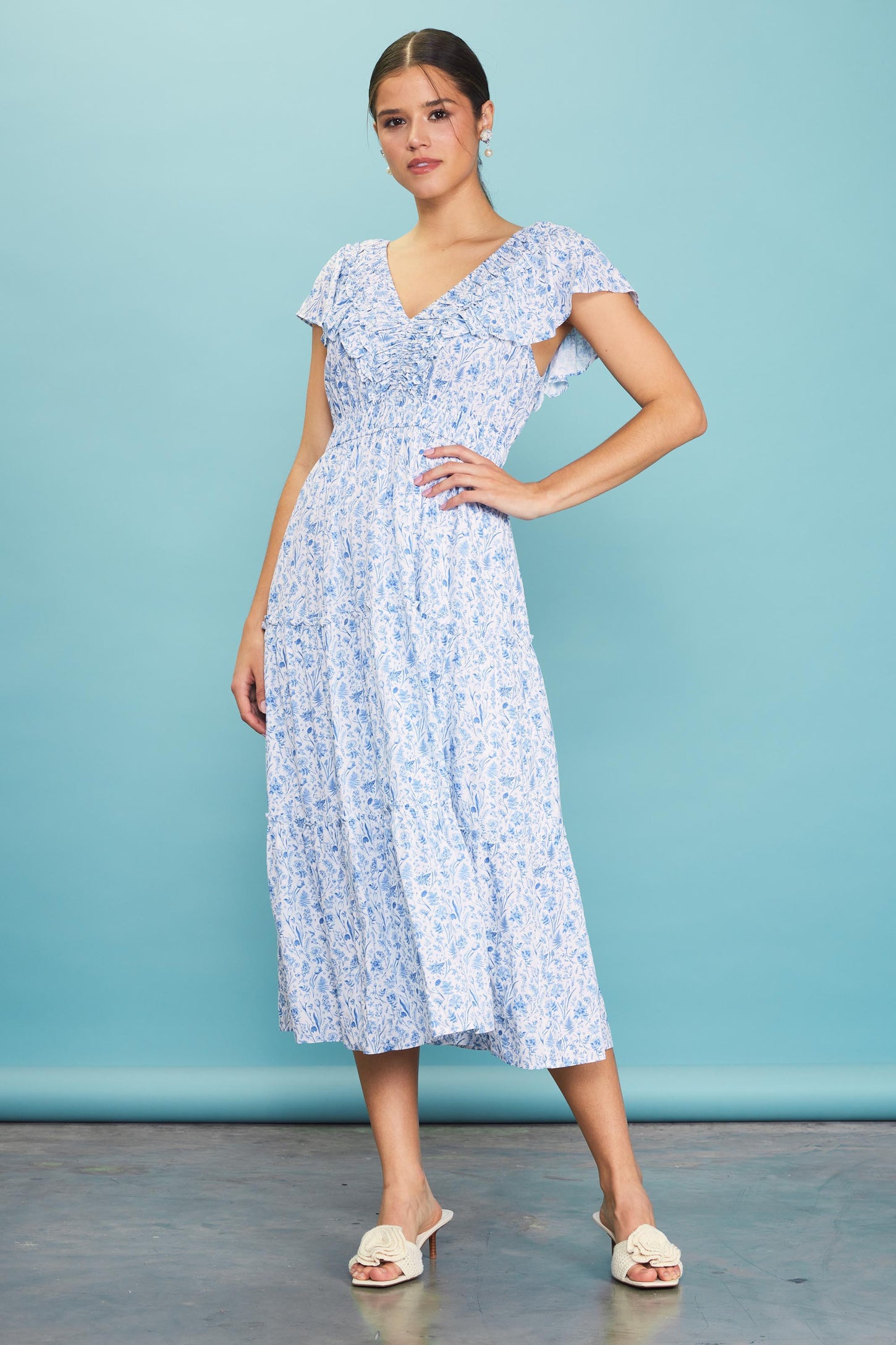 woman wearing a blue floral midi dress with ruffled sleeves and a v-neckline