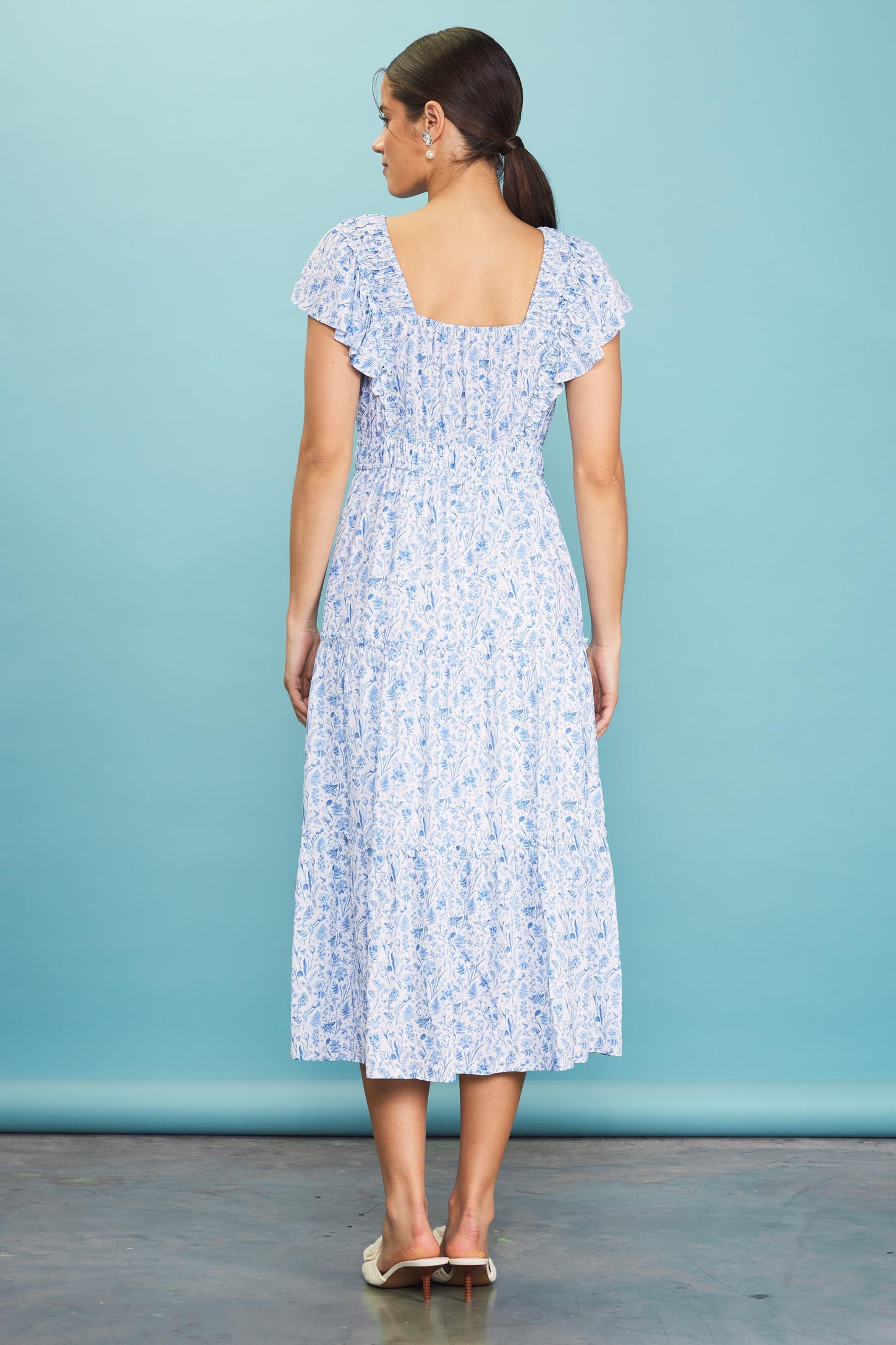 woman wearing a blue floral midi dress with short ruffled sleeves and a smocked back