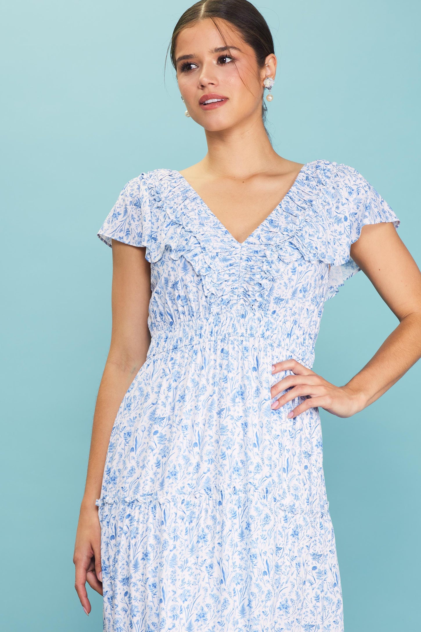woman wearing a blue and white floral print dress with ruffled sleeves and a smocked bodice