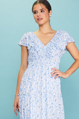 woman wearing a blue and white floral print dress with ruffled sleeves and a smocked bodice