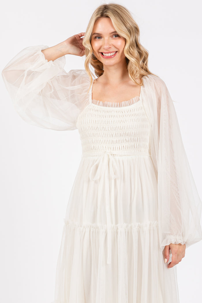 woman wearing a cream puff sleeve dress with a smocked bodice and tie detail at the waist