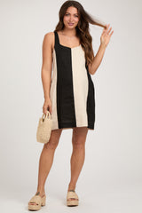woman wearing a striped black and beige maternity dress and holding a small woven bag