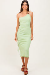 woman wearing a light green one-shoulder midi dress with ruched detail and drawstring side