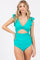 woman wearing a teal one-piece swimsuit with ruffle sleeves and a cut-out detail on the waist