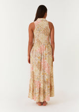 woman wearing a sleeveless floral maxi dress with a gathered waist and tiered skirt, viewed from the back