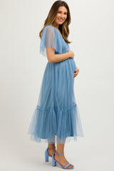 woman wearing a light blue maternity tulle dress with a tiered skirt and holding her baby bump