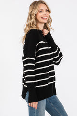 woman wearing a black and white striped oversized sweater with long sleeves and side slits, paired with blue jeans