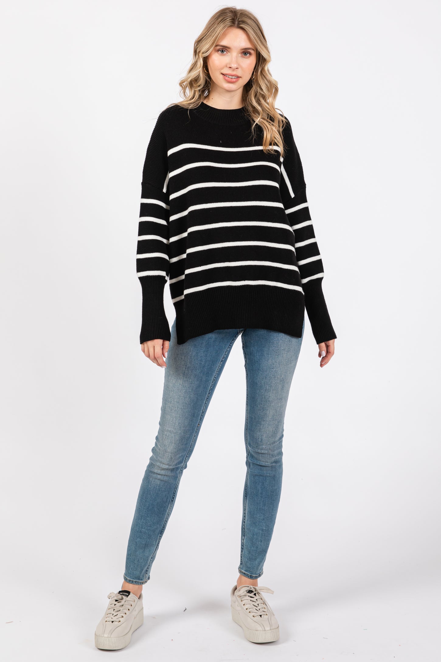 woman wearing a black and white striped oversized sweater with long sleeves and light blue skinny jeans