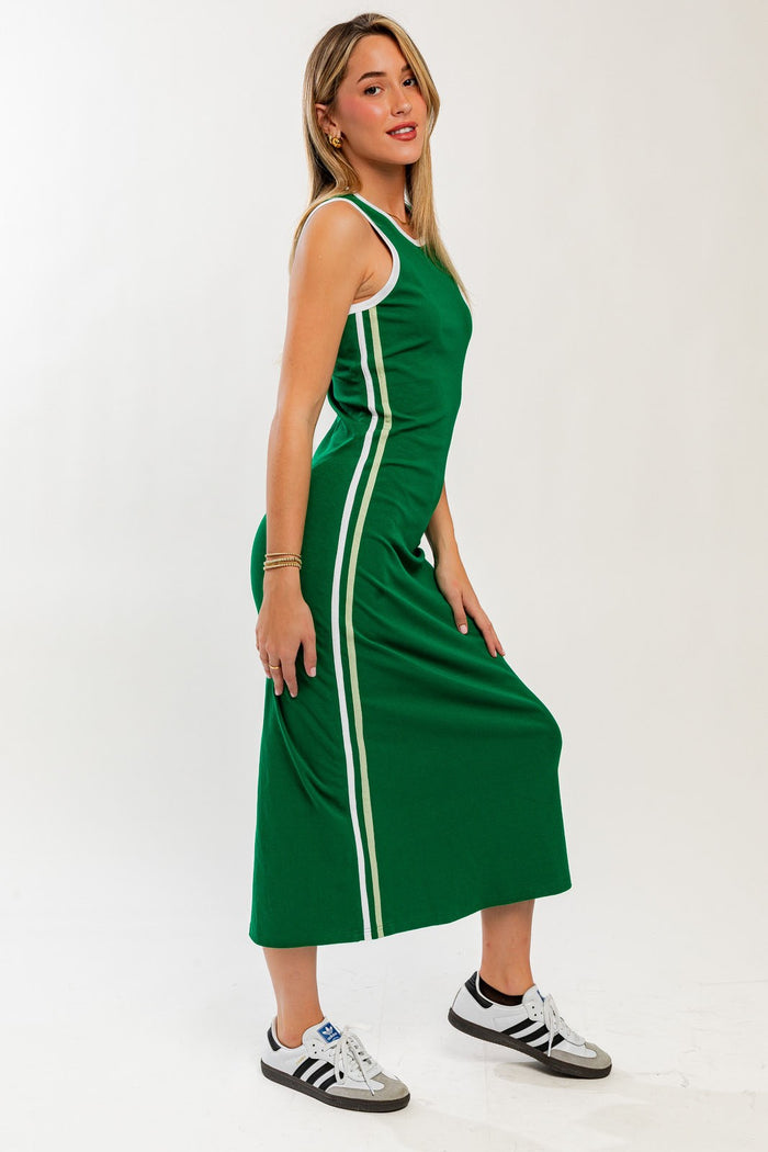 woman wearing a green athletic maxi dress with white side stripes and paired with white sneakers