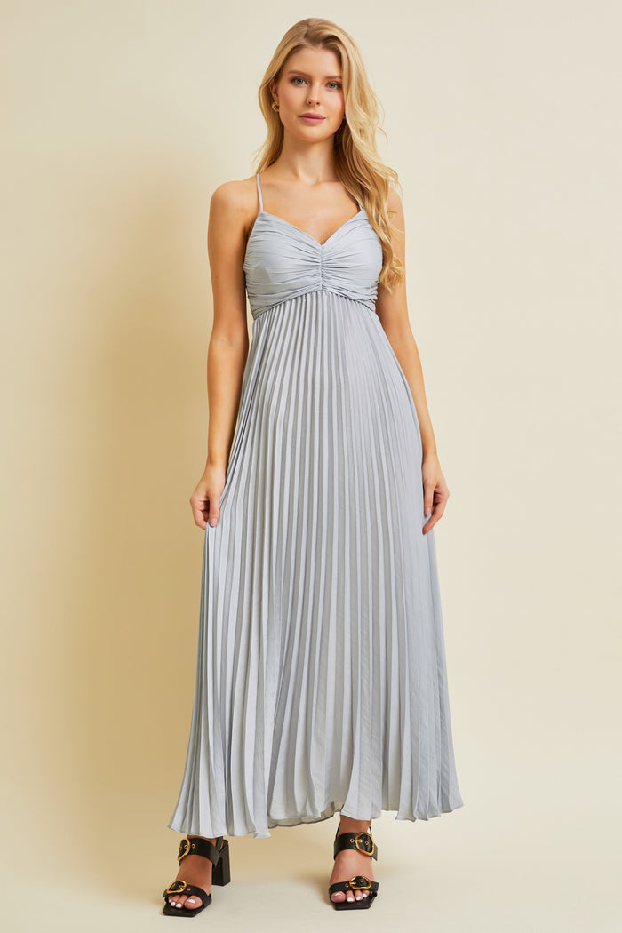 woman wearing a light grey pleated maxi dress with spaghetti straps and a sweetheart neckline