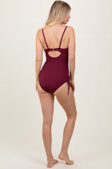 woman wearing a burgundy ribbed one-piece swimsuit with adjustable straps and side ties, viewed from the back