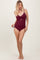 woman wearing a burgundy ribbed one-piece swimsuit with adjustable side ties and a front twist detail