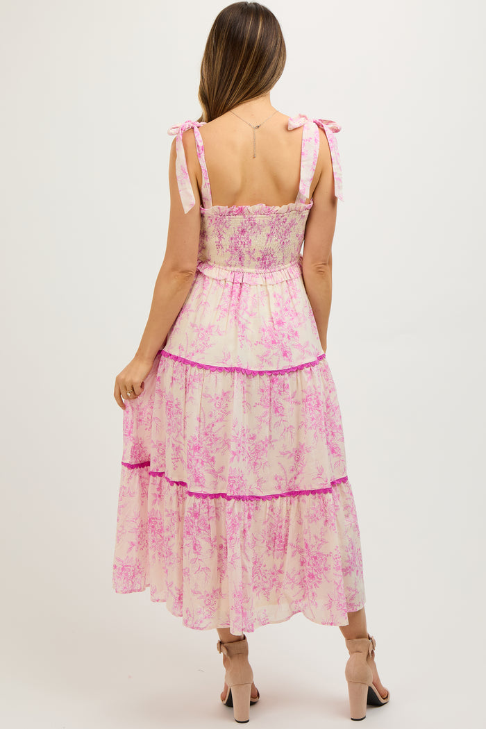 woman wearing a pink floral maternity maxi dress with tie straps and a tiered design, showing her baby bump