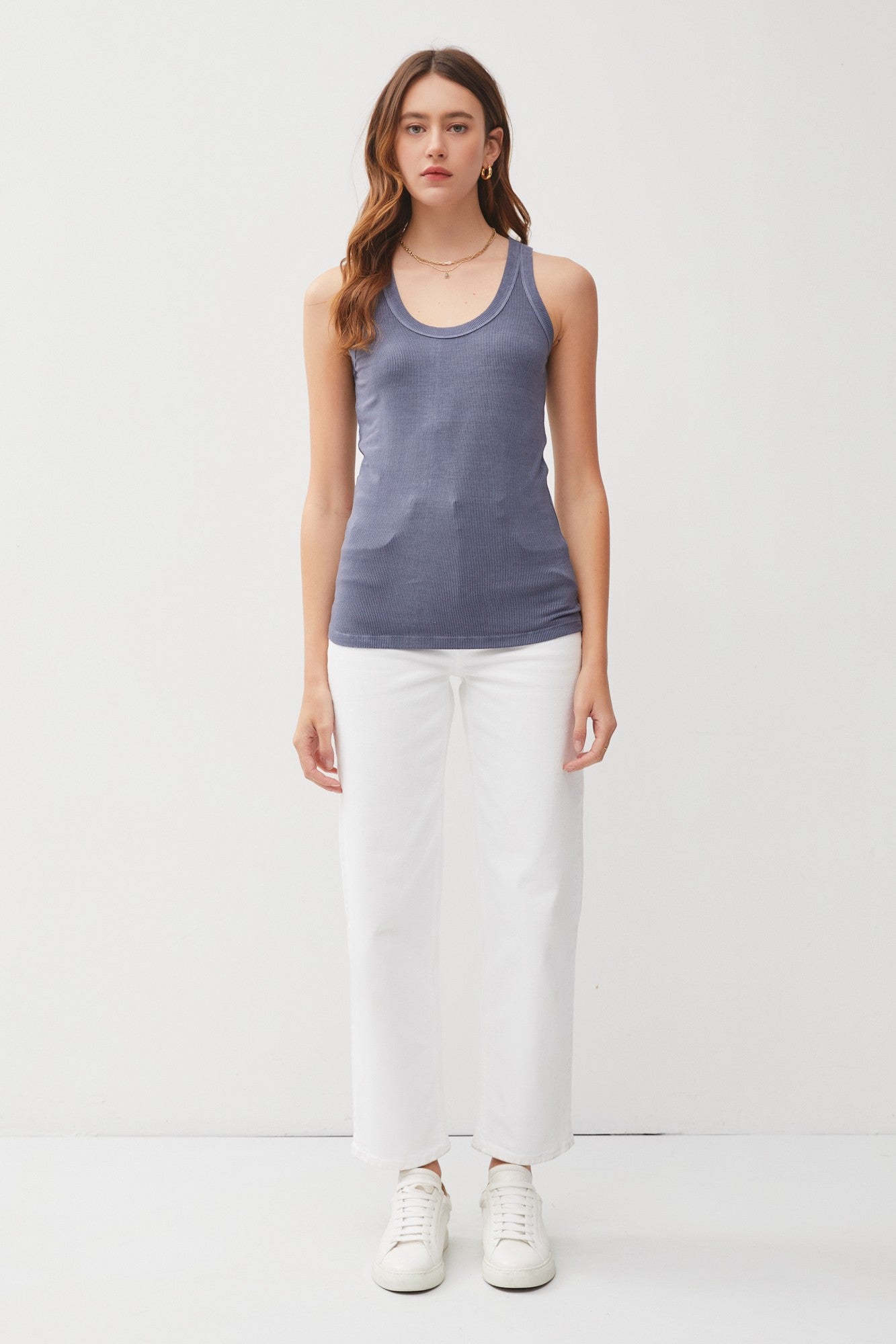 woman wearing a dark blue fitted tank top and white wide-leg pants with sneakers