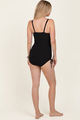 woman wearing a black ribbed one-piece swimsuit with adjustable side ties, viewed from the back