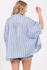 woman wearing a blue and white striped loose-fitting oversized shirt with rolled sleeves and a curved hem
