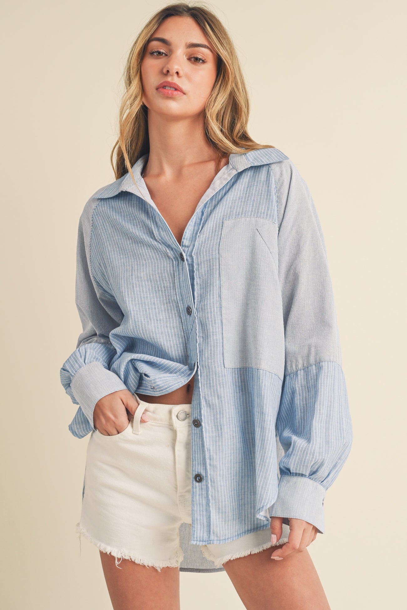 woman wearing a blue and white striped button-up shirt with long sleeves and light shorts