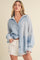 woman wearing a blue and white striped button-up shirt with long sleeves and light shorts