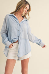 woman wearing a light blue striped oversized button-up shirt and white distressed denim shorts
