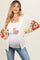 woman wearing a cream crochet maternity cardigan with colorful patterned sleeves and holding her baby bump