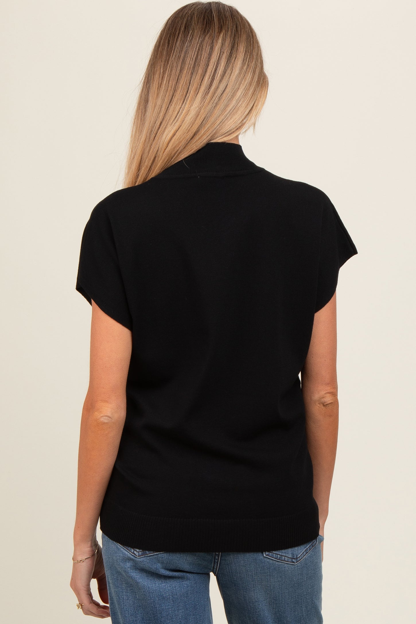woman wearing a black short sleeve maternity sweater, seen from the back