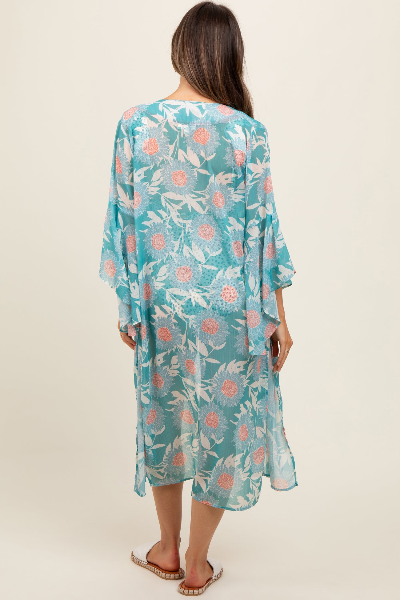 woman wearing a sheer turquoise maternity kimono with floral print, shown from the back