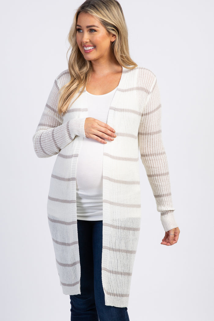 smiling pregnant woman wearing a white and grey striped long maternity cardigan over a white top and jeans