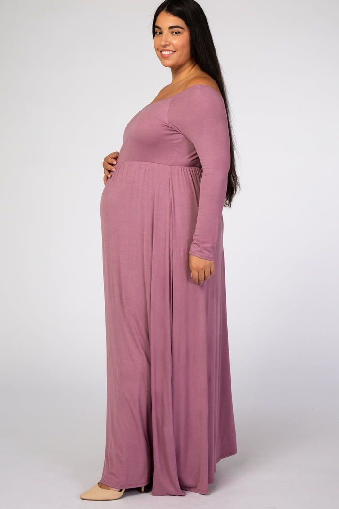 Pregnant woman in a long sleeve mauve maternity maxi dress posing against a white background
