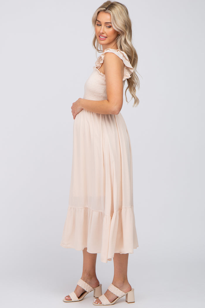 pregnant woman in cream smocked maternity midi dress with ruffle sleeves and block heel sandals
