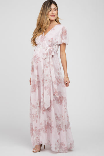 pregnant woman wearing a light pink floral maternity maxi dress with a waist tie and short sleeves