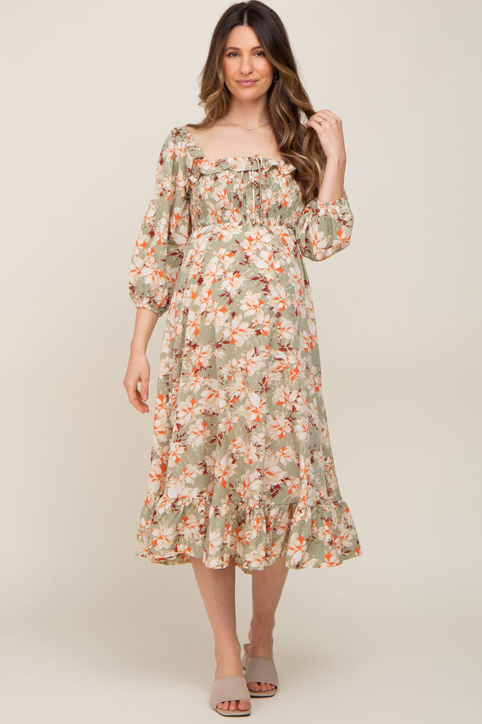 woman wearing a floral maternity dress with a square neckline and puff sleeves, styled with a ruffled hem
