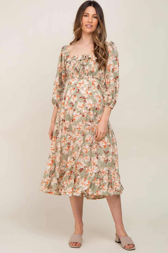 woman wearing a floral print maternity dress with a square neckline and puffed sleeves, showcasing her baby bump