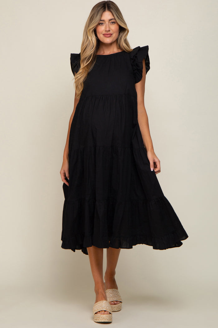 woman wearing a black tiered maternity midi dress with ruffle sleeves and woven platform sandals