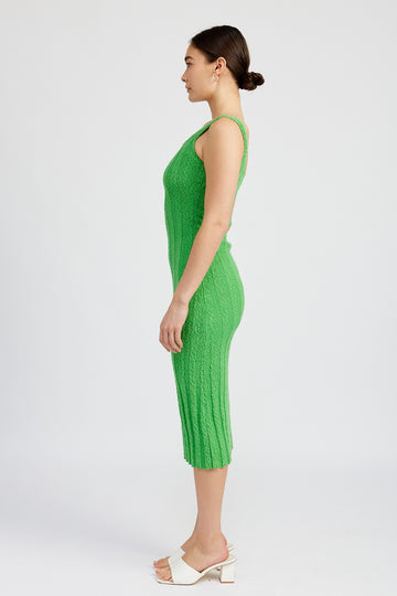woman wearing a form-fitting green knitted midi dress with a ribbed texture and spaghetti straps